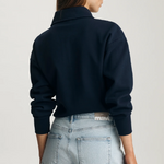 Person wearing a navy sweater and light blue denim shorts on a plain background