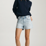 Woman wearing a navy sweater and light blue denim shorts on a white background