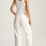 Woman wearing a white tank top and wide-leg pants on a plain background