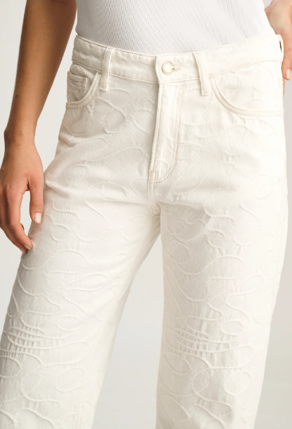 White textured pants worn by a person on a light gray background