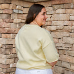 yellow short sleeve knit sweater with rolled edges and white denim