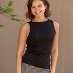 Woman wearing a black sleeveless top and checkered shorts against a beige background