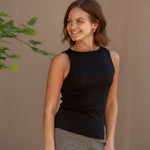 Woman wearing a black sleeveless top and black and white checkered shorts 
