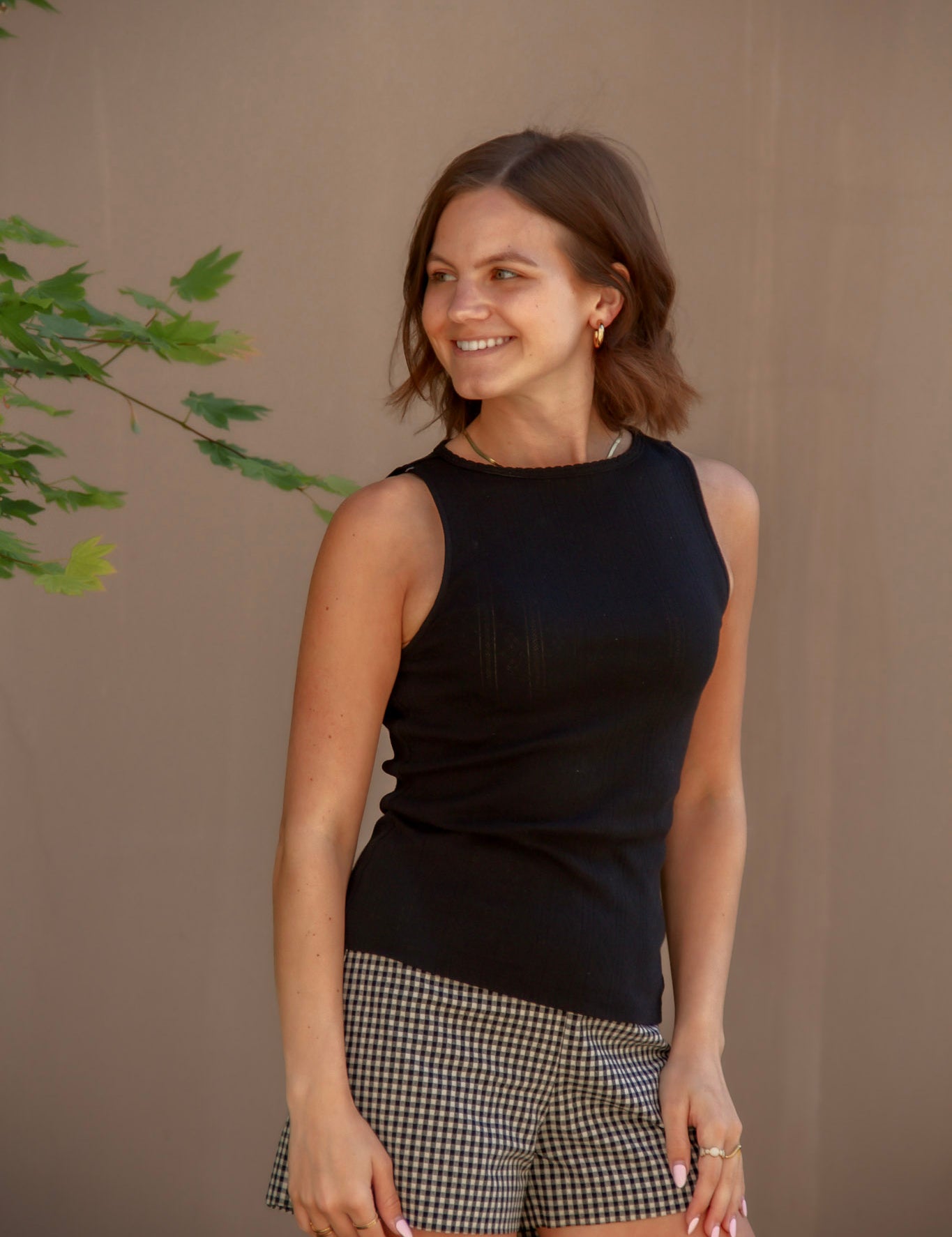 Woman wearing a black sleeveless top and black and white checkered shorts 