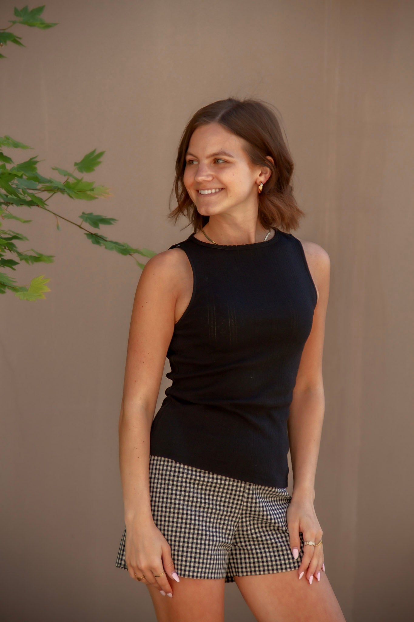 Woman wearing a black sleeveless top and black and white checkered shorts 