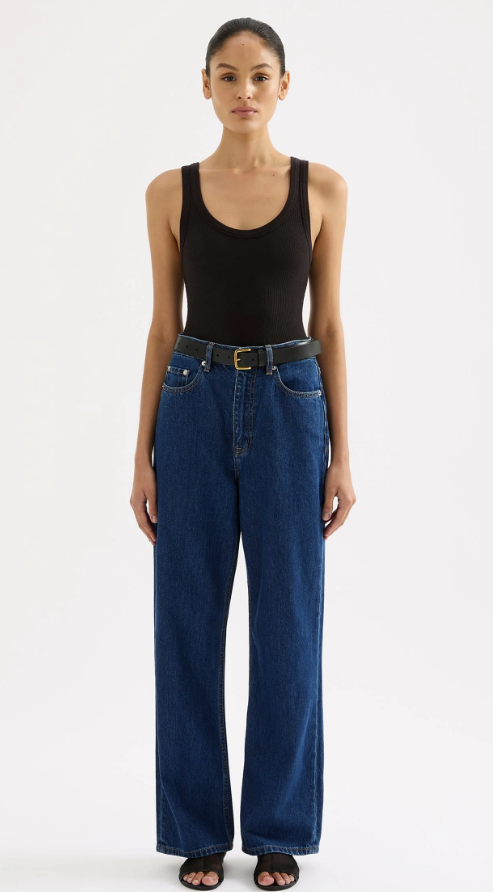 woman wearing a black scoop neck tank top with dark wash jeans