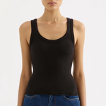 Woman wearing a black tank top and blue jeans on a white background