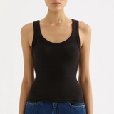 Woman wearing a black tank top and blue jeans on a white background