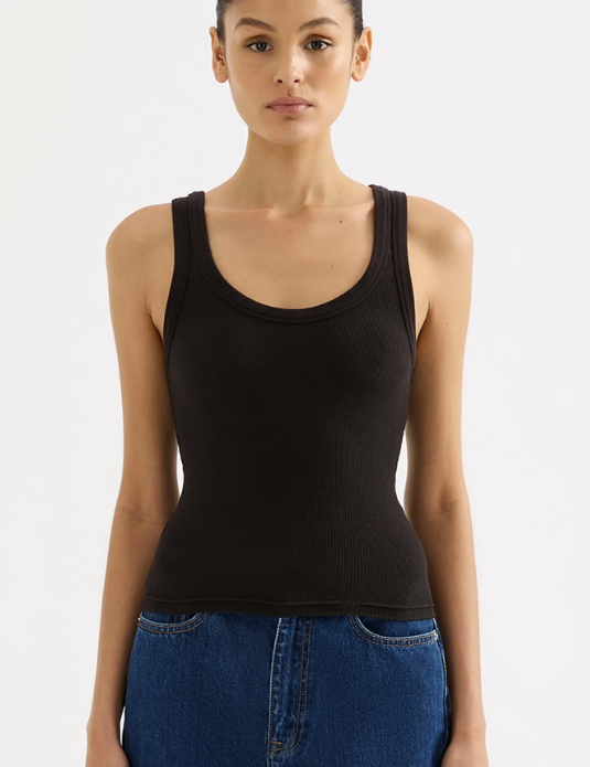 Woman wearing a black tank top and blue jeans on a white background
