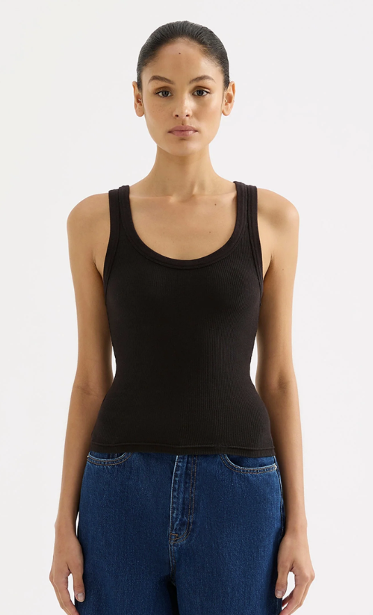 Woman wearing a black tank top and blue jeans on a white background