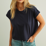 Woman wearing a navy boxy t-shirt  with cuffed sleeves and blue jeans 