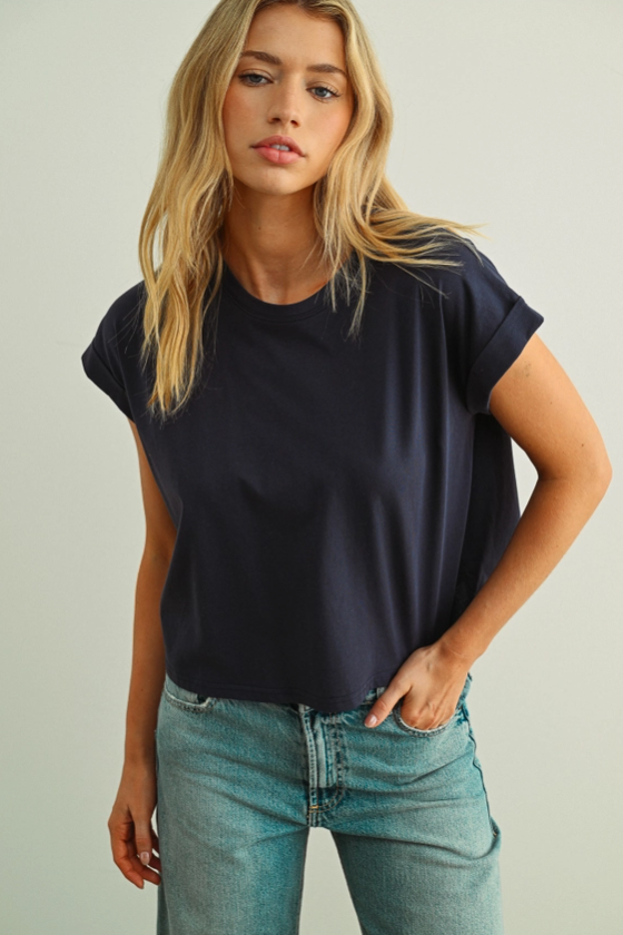 Woman wearing a navy boxy t-shirt  with cuffed sleeves and blue jeans 