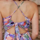 Floral midi dress with purple, green, coral and white colors. Pleated skirt and adjustable straps. backside of dress with tie-back detail and a slight open-back