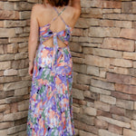 Floral midi dress with purple, green, coral and white colors. Pleated skirt and adjustable straps. backside of dress with tie-back detail and a slight open-back