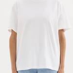 A girl in a white boxy oversized boyfriend style tshirt untucked with light wash jeans