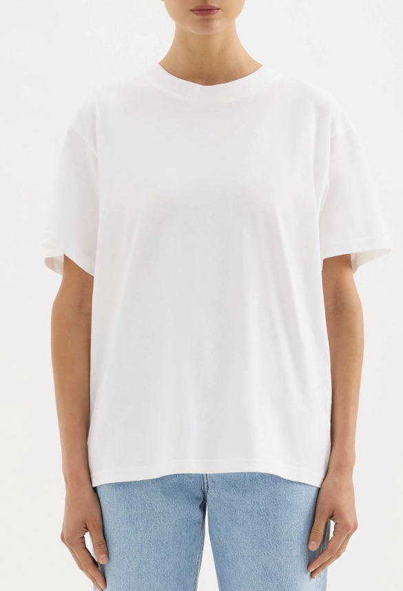 A girl in a white boxy oversized boyfriend style tshirt untucked with light wash jeans