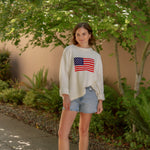 cream american flag sweater with light wash denim shorts