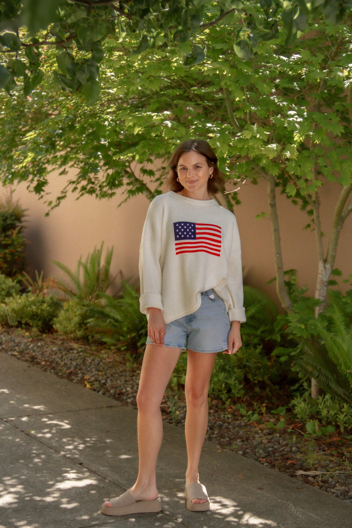 cream american flag sweater with light wash denim shorts