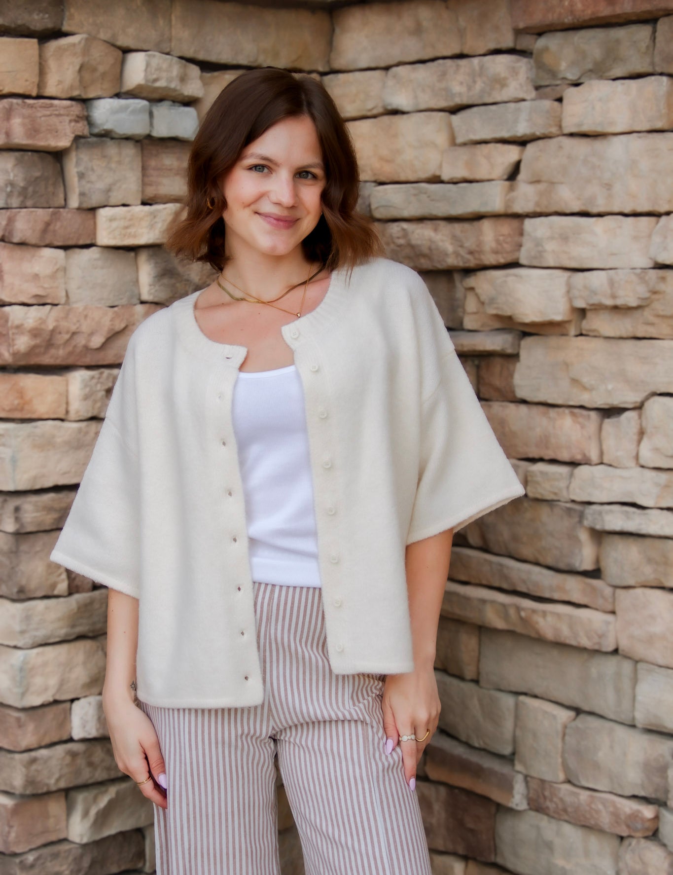 cream soft short sleeve sweater cardigan with buttons down the front and stripe pant