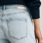 Person wearing light blue denim shorts with a visible Mavi brand label on a neutral background