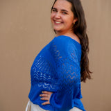 Woman wearing a blue knitted sweater against a beige background