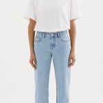 A girl in a white boxy oversized boyfriend style tshirt tucked in to light wash jeans