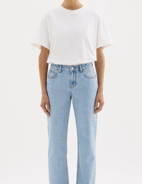 A girl in a white boxy oversized boyfriend style tshirt tucked in to light wash jeans