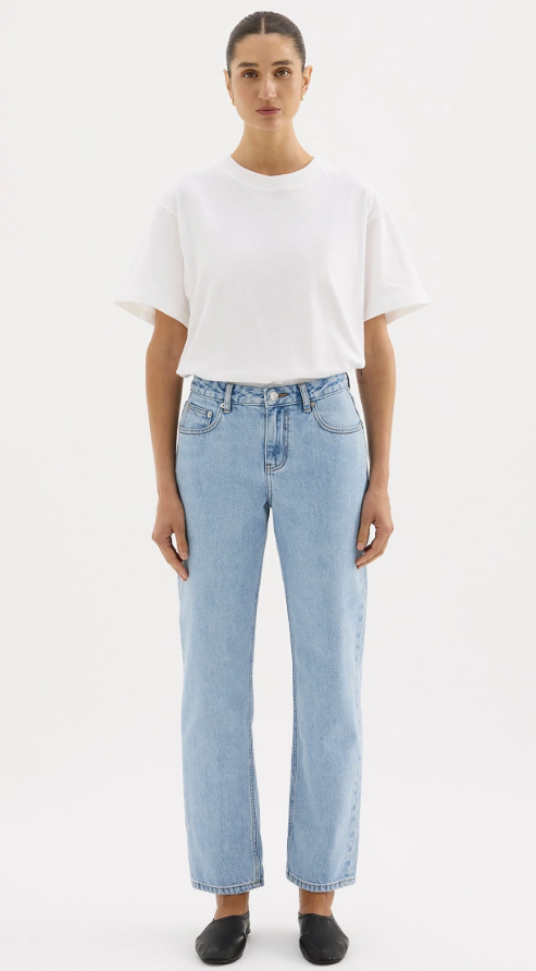 A girl in a white boxy oversized boyfriend style tshirt tucked in to light wash jeans