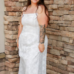 woman wearing a white spaghetti strap midi dress with embroidered details
