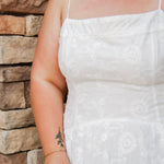 woman wearing a white spaghetti strap midi dress with embroidered details