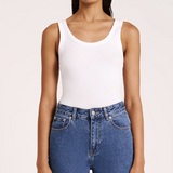 woman wearing white scoop neck ribbed tank top with medium wash jeans