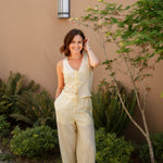 yellow linen tie front tank top and yellow linen drawstring pants paired with white sandals and gold jewelry