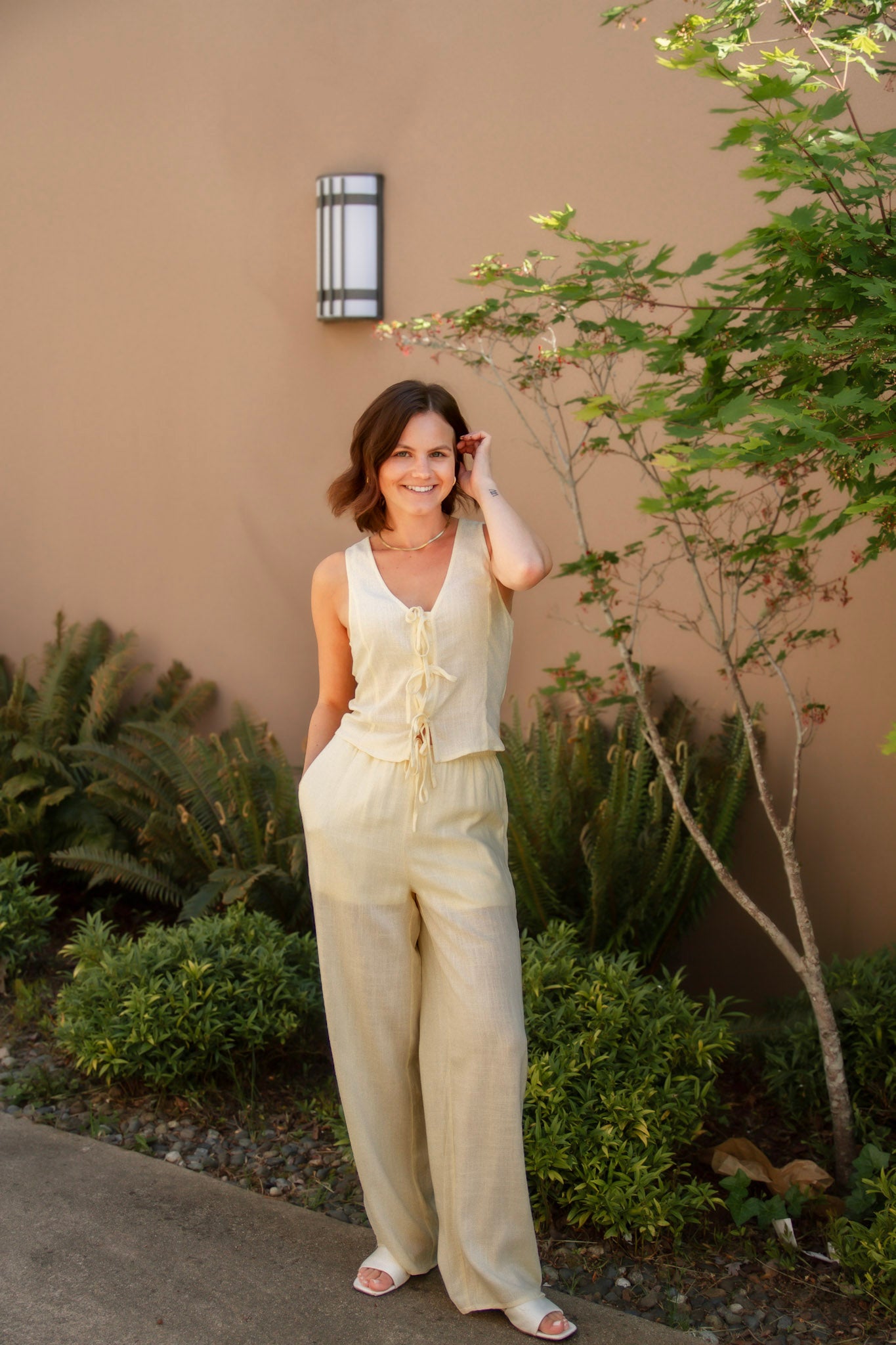 yellow linen tie front tank top and yellow linen drawstring pants paired with white sandals and gold jewelry
