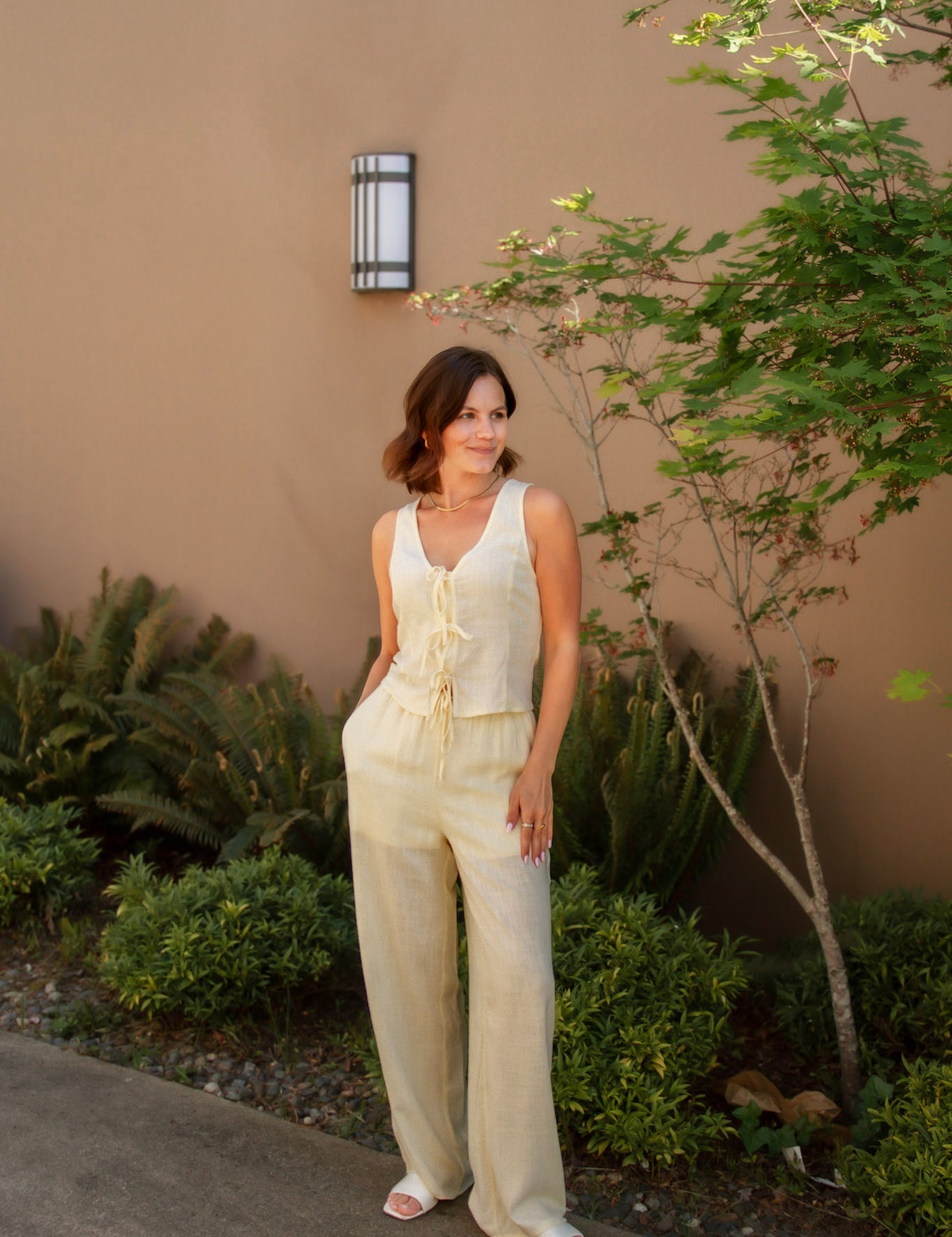 yellow linen tie front tank top and yellow linen drawstring pants paired with white sandals and gold jewelry