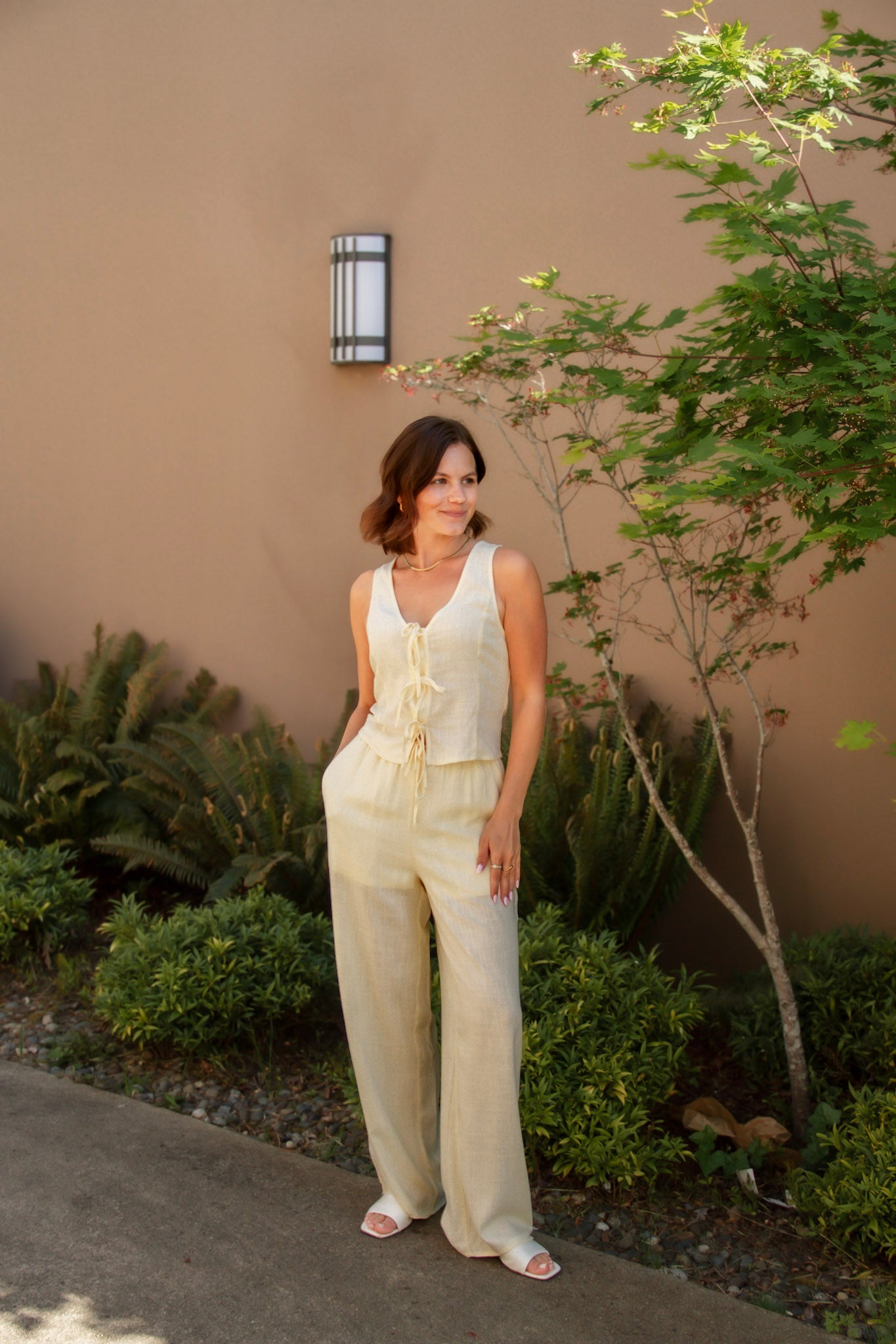 yellow linen tie front tank top and yellow linen drawstring pants paired with white sandals and gold jewelry