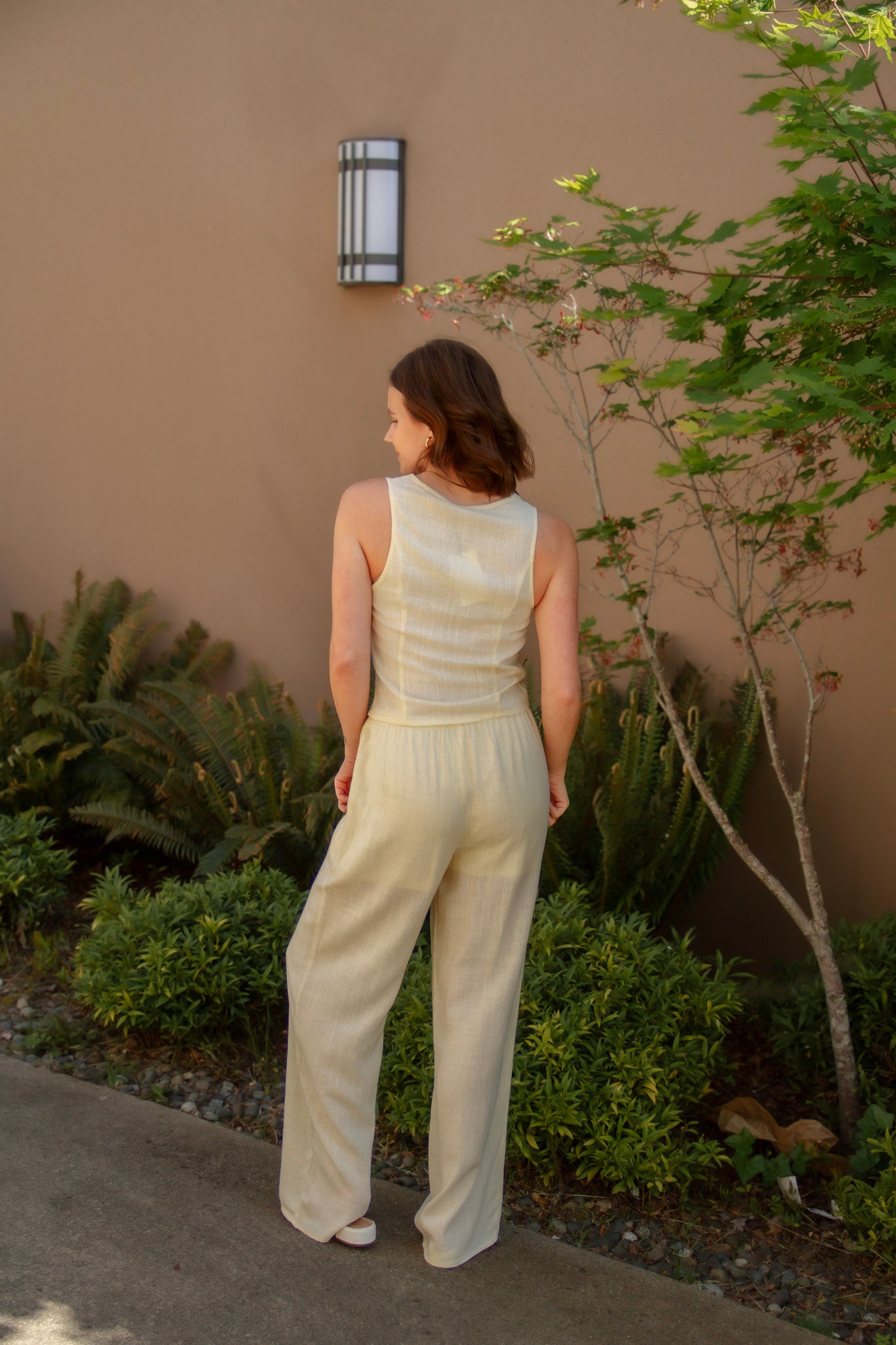 yellow linen tie front tank top and yellow linen drawstring pants paired with white sandals and gold jewelry