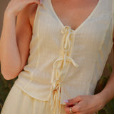 yellow sleeveless tank top with ties on the front and a matching yellow drawstring linen pant